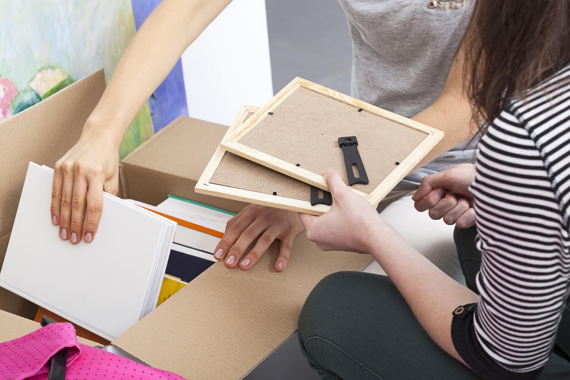 People holding picture frames above a cardboard box