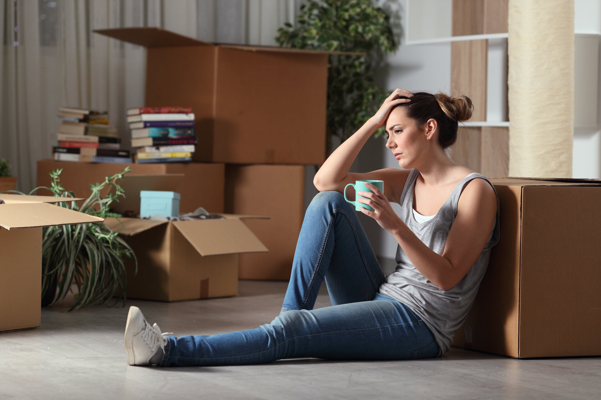 A stressed out woman sitting on the floor with boxes