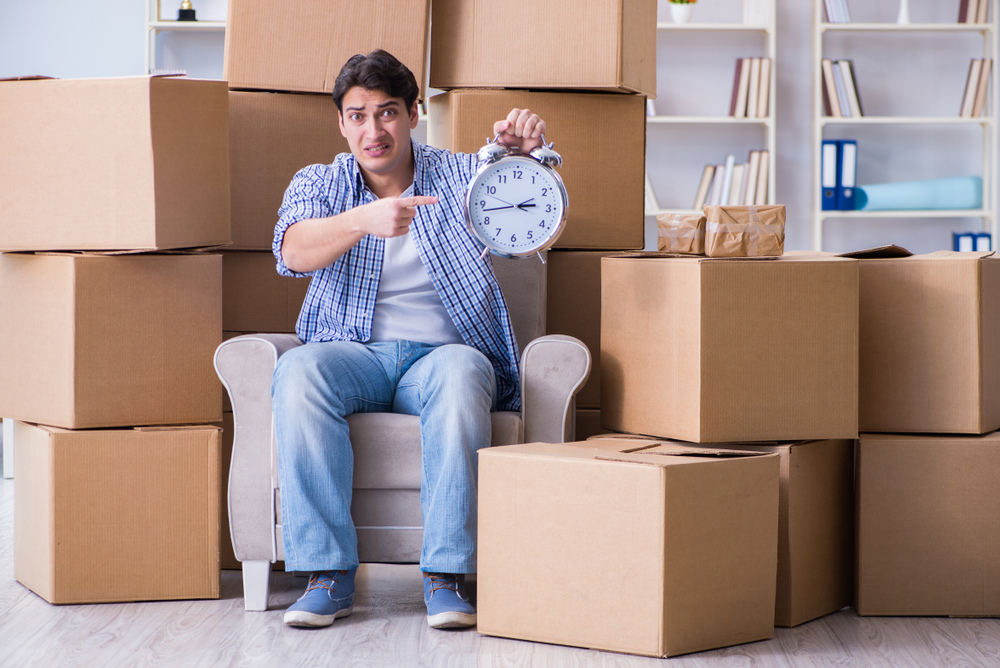 A man sitting on boxes holding a clock