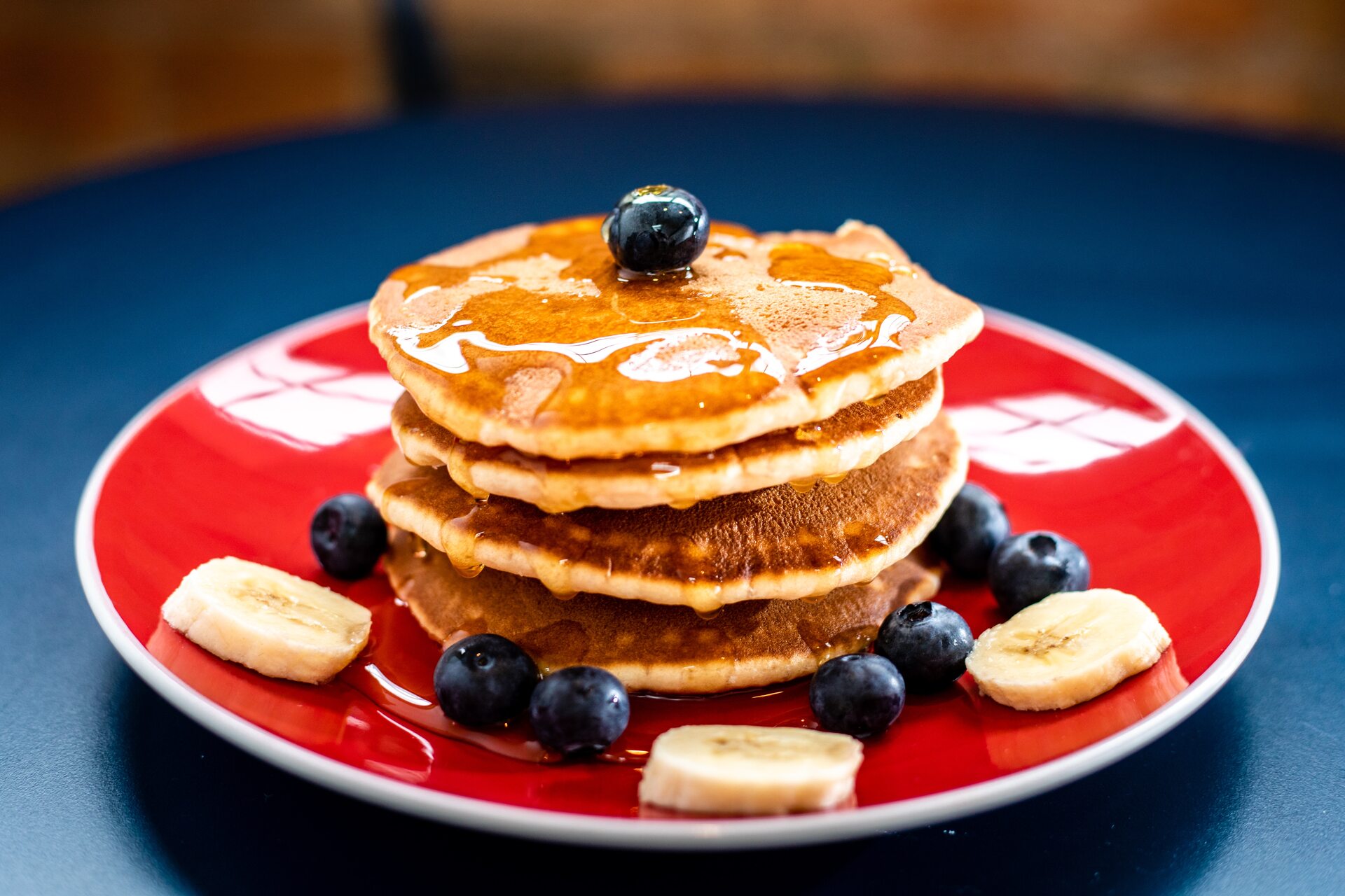 Pancakes with blueberries, banana slices, and maple syrup on a plate
