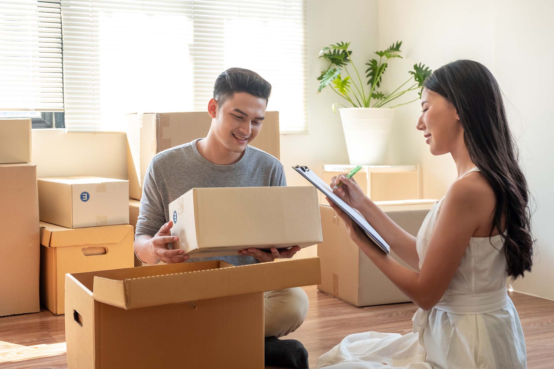 couple packing while woman is creating a checklist