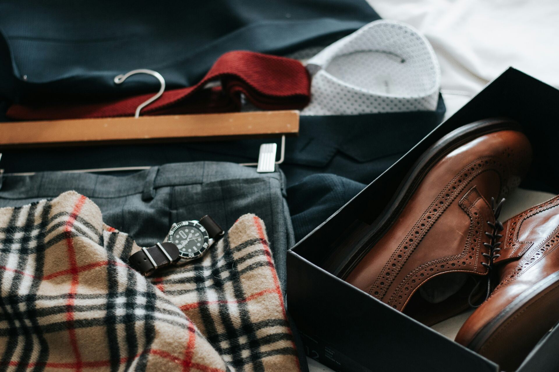 A pair of shoes in a box next to a laid-out suit