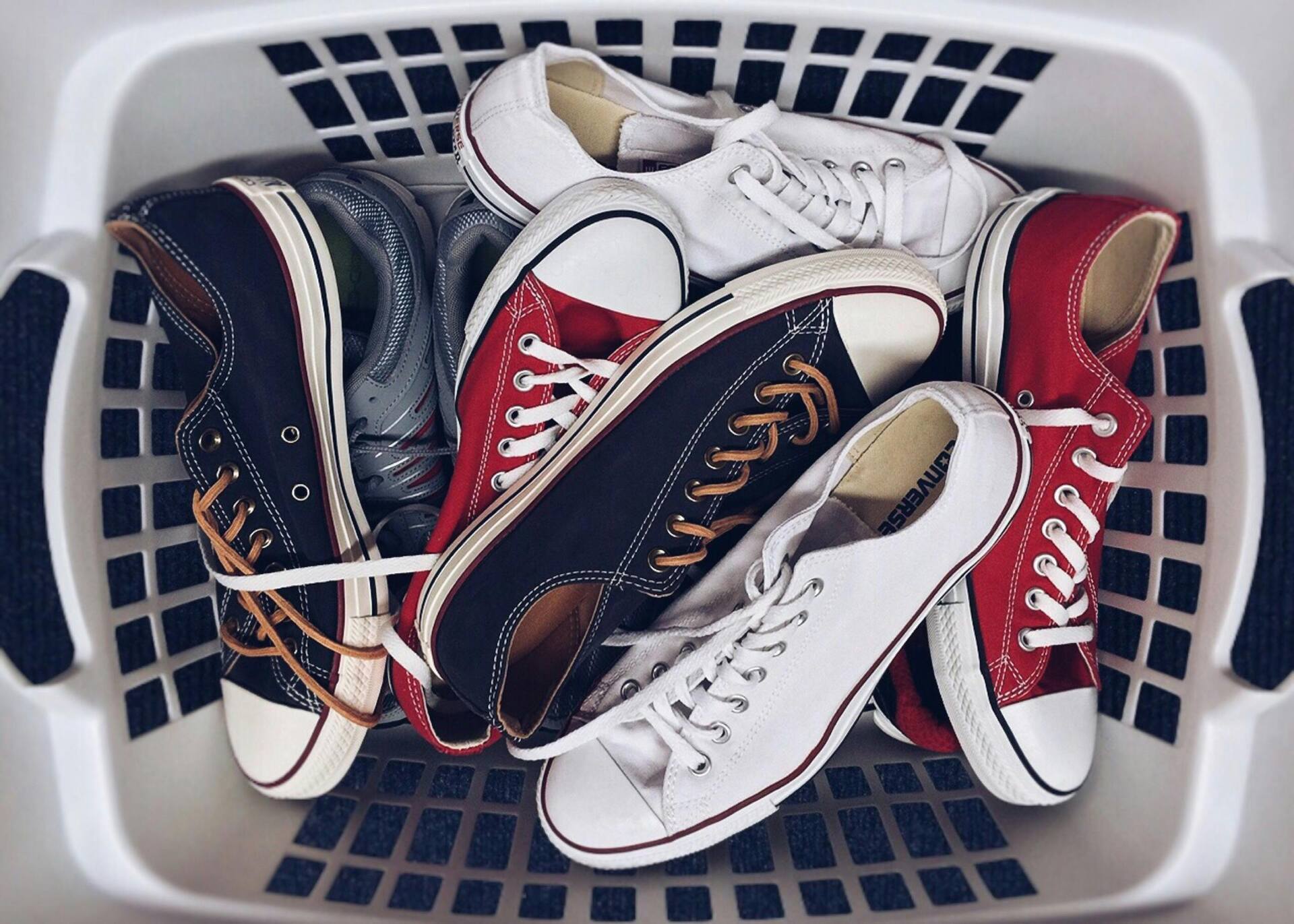 Several pairs of shoes and sneakers in a plastic basket