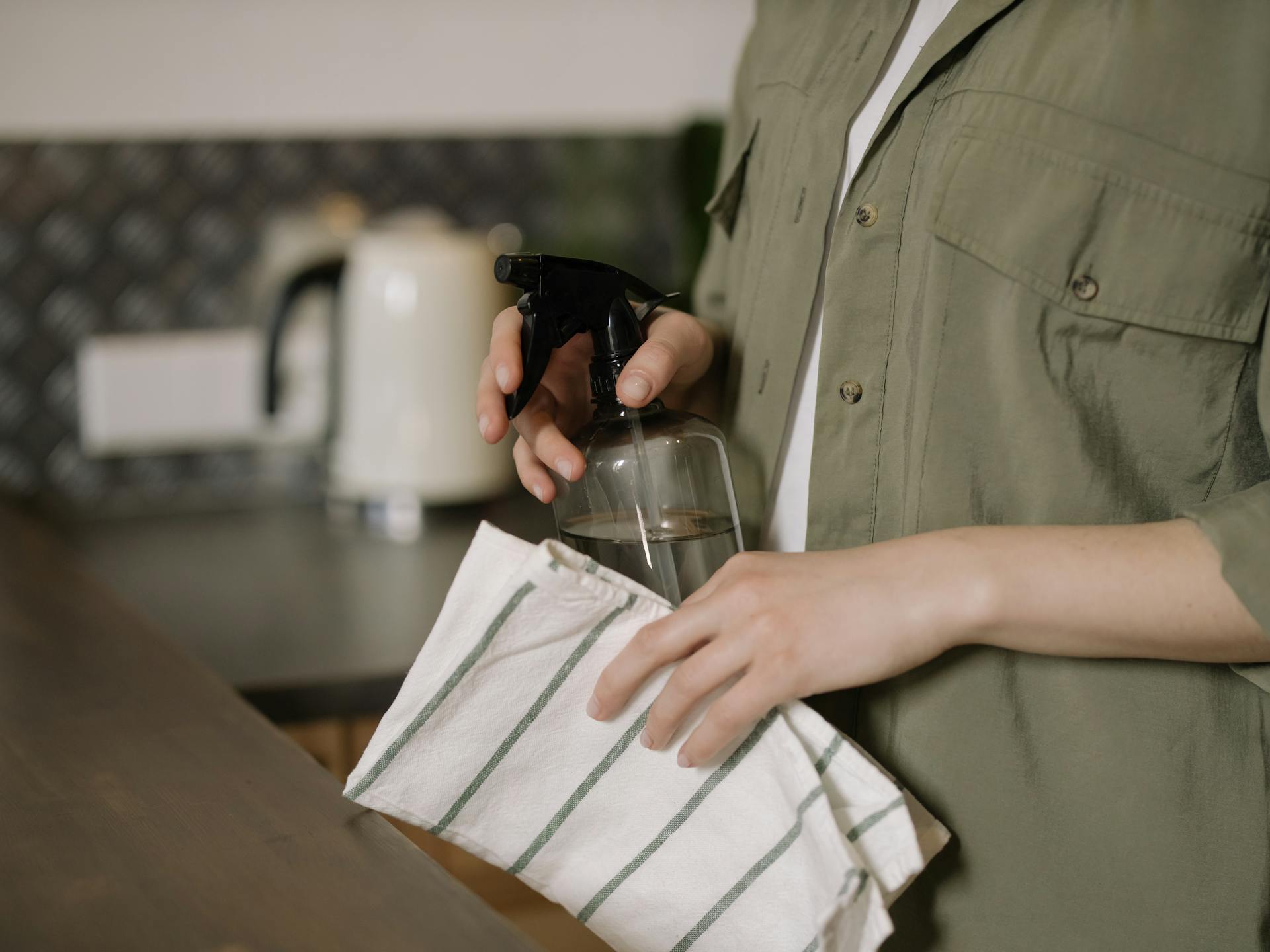 A woman holding a rag and a cleaning solution