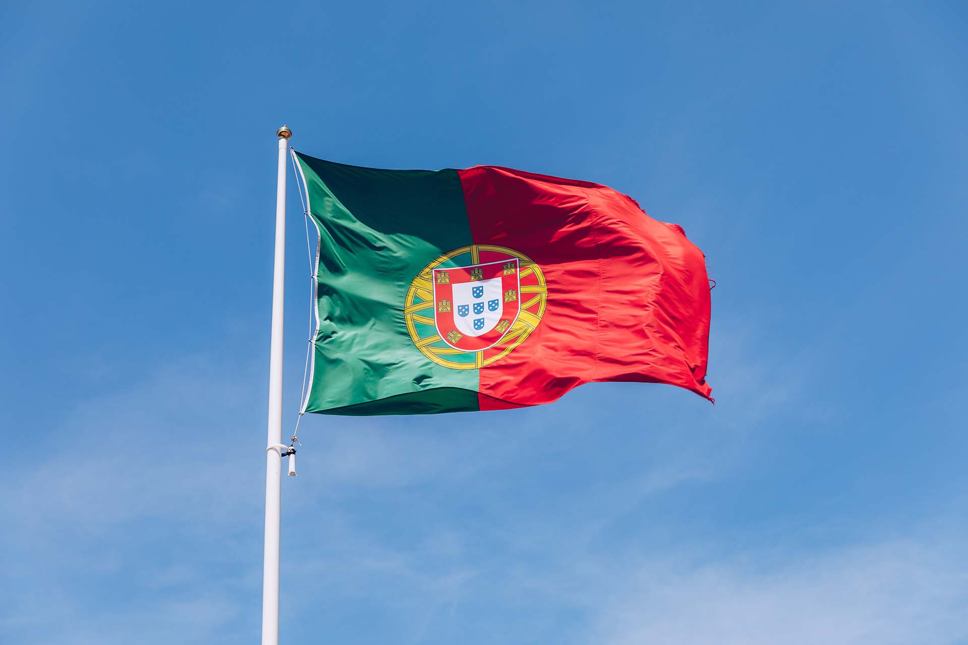 Beautiful large Portuguese flag waving in the wind against blue sky. Portuguese Flag Waving Against Blue Sky. Flag of Portugal waving, against blue sky