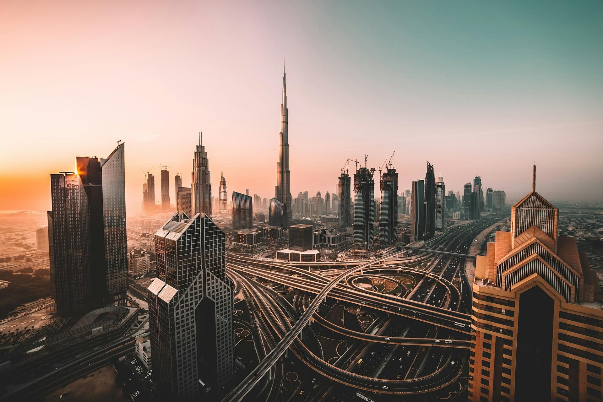 Burj Khalifa skyscraper and busy multi-lane highway illuminated at dusk in Dubai.